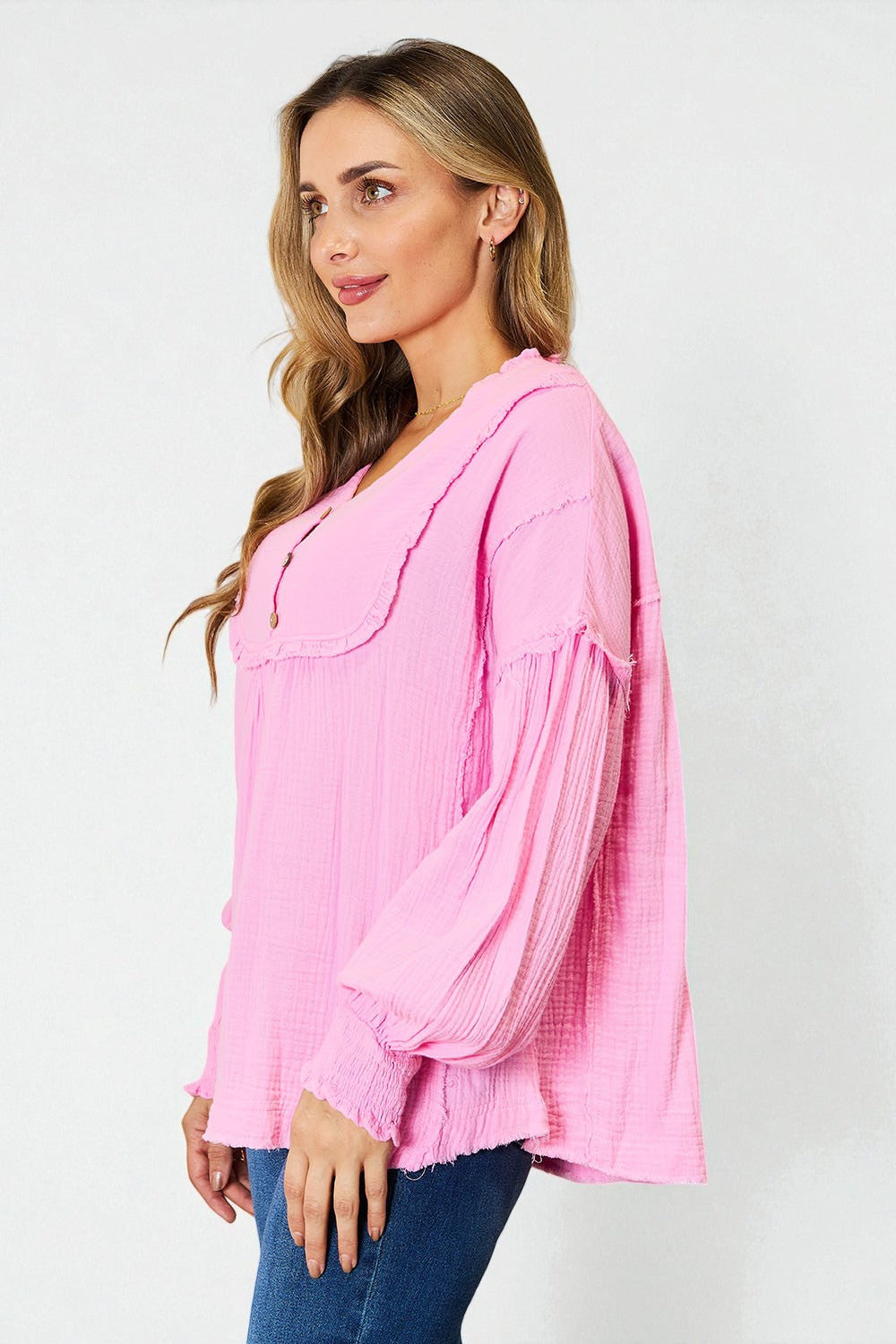 Woman wearing a pink blouse with long sleeves on a white background