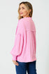 Woman wearing a pink textured blouse with blue jeans on a white background