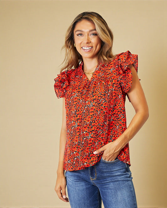 Woman wearing a red floral blouse and blue jeans against a beige background