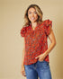 Woman wearing a red floral blouse and blue jeans against a beige background
