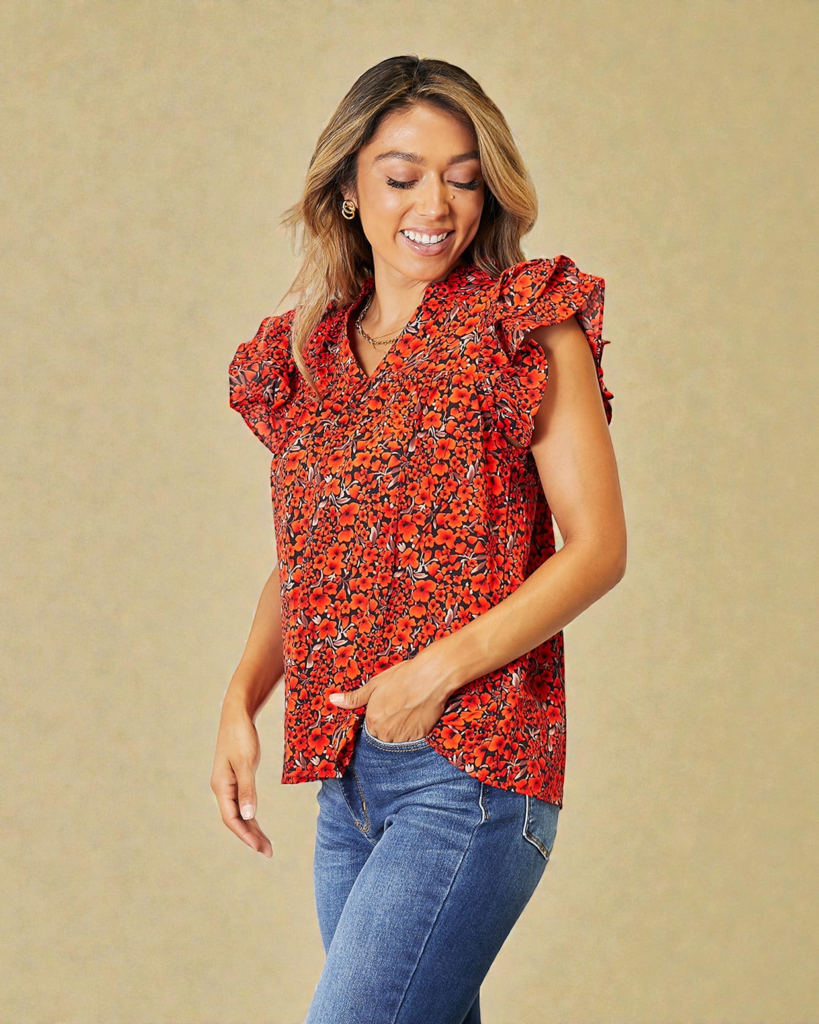 Woman wearing a red floral blouse and blue jeans on a beige background