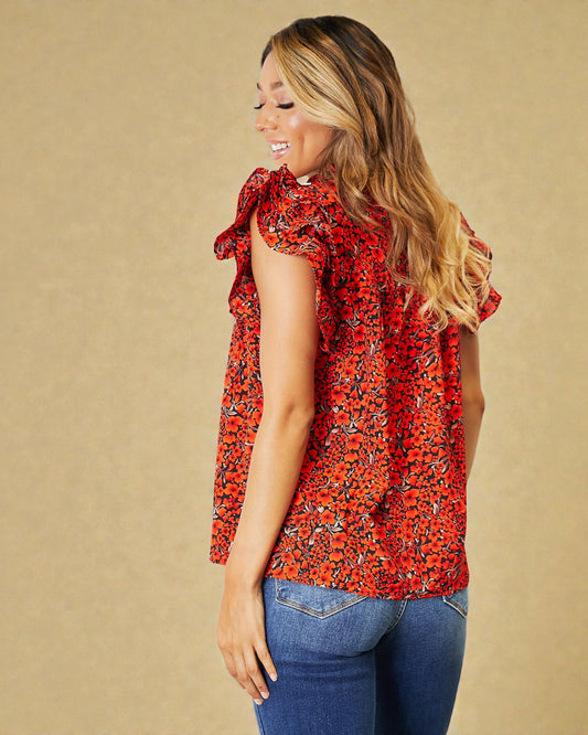 Woman wearing a red floral top with a beige background