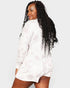 Woman wearing a white outfit with long, curly hair on a plain background