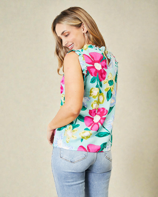 Woman wearing a colorful floral sleeveless top against a beige background