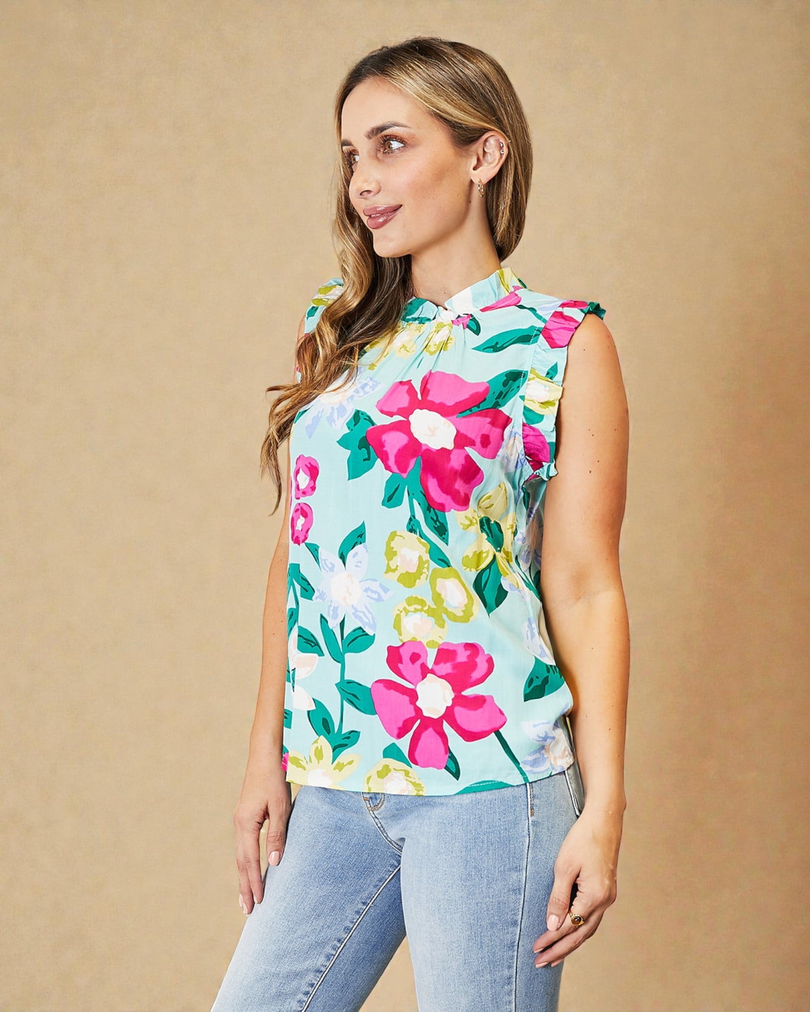 Woman wearing a sleeveless floral top with a beige background