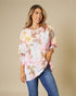 Woman wearing a floral blouse and jeans against a beige background