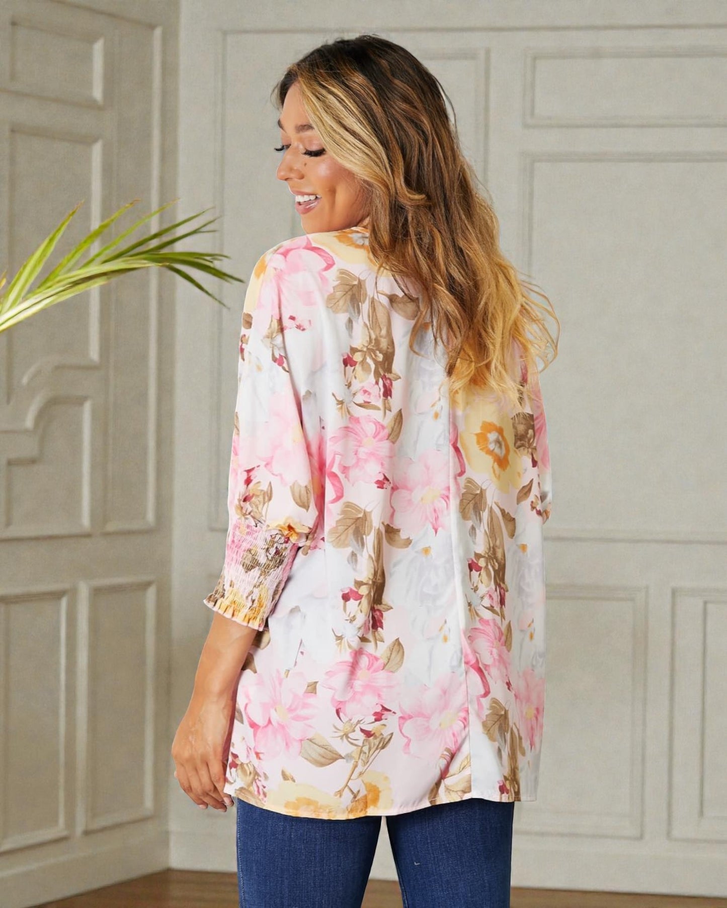 Woman wearing a floral kimono-style top in a room with decorative paneling.