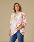 Woman wearing a floral blouse and jeans against a beige background