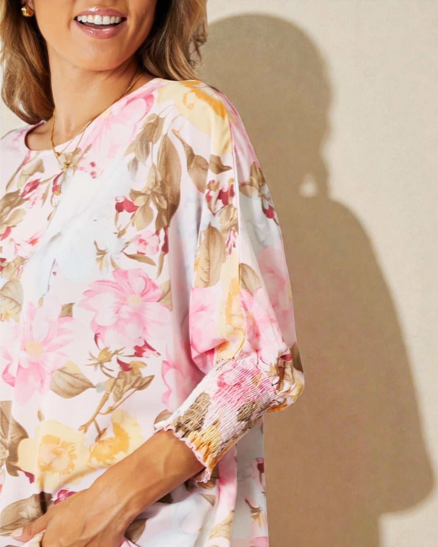 Woman wearing a floral blouse with a soft shadow on a beige background