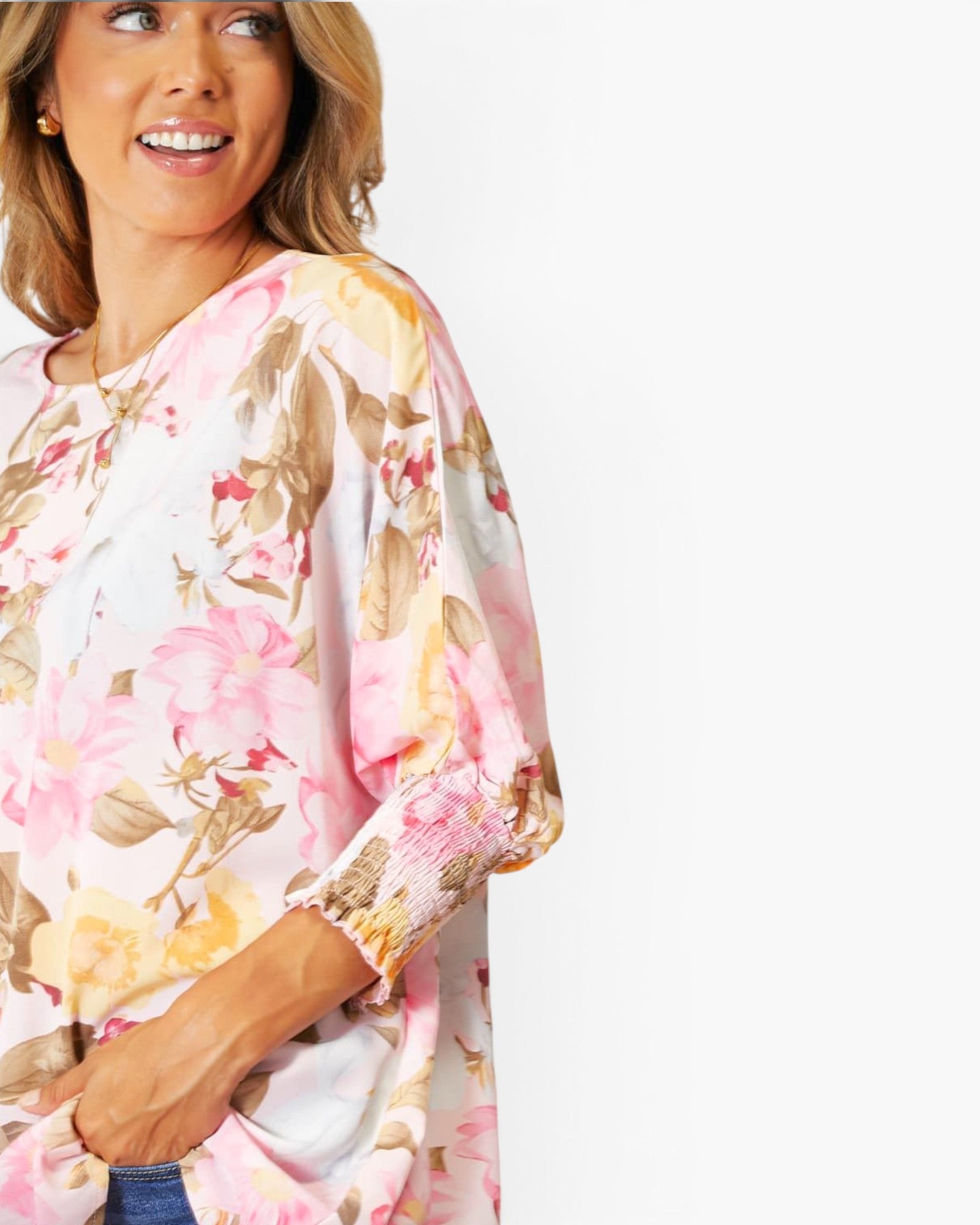 A woman wearing a loose white blouse with a pink, yellow, and brown floral print, shown against a plain white background.
