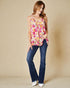 Woman wearing a floral top and blue jeans against a beige background