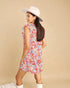Woman wearing a floral dress and white hat against a beige background