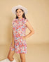 Woman wearing a floral dress and white hat against a beige background