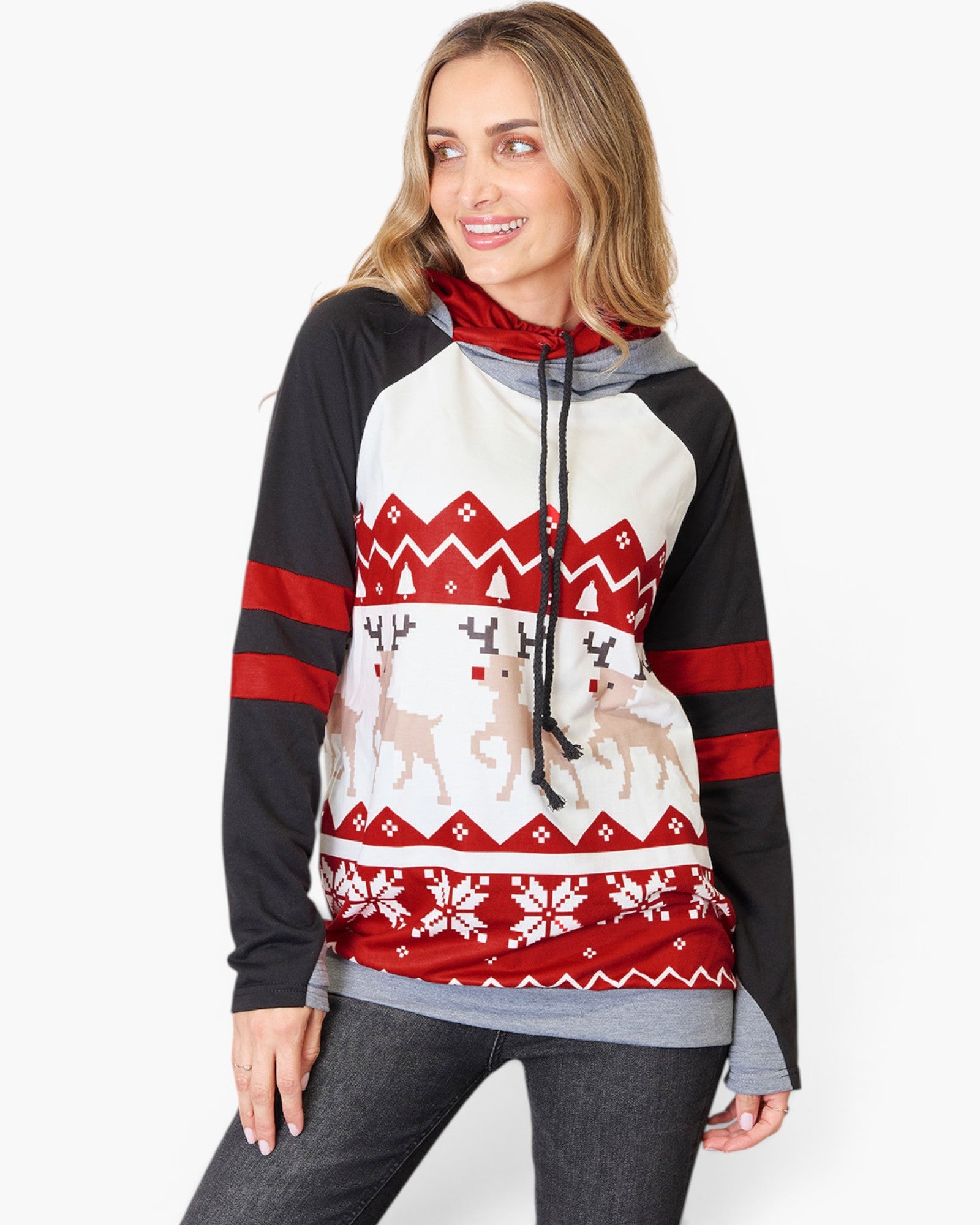 A woman wearing a holiday-themed raglan hoodie with a red, white, and black Nordic pattern featuring reindeer and snowflakes, paired with gray jeans against a plain white background.