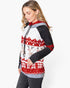 A woman wearing a long-sleeve hooded sweatshirt with a festive holiday pattern. The hoodie features a white body with red and black geometric mountain patterns, a central panel with beige reindeer, and a red and white snowflake pattern at the bottom.