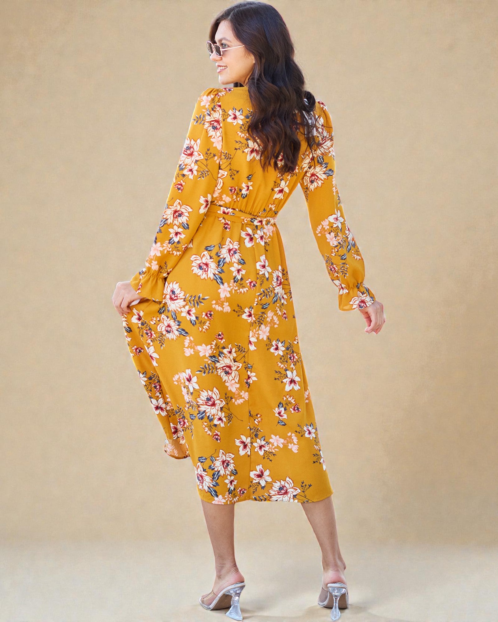 Woman wearing a yellow floral dress against a beige background