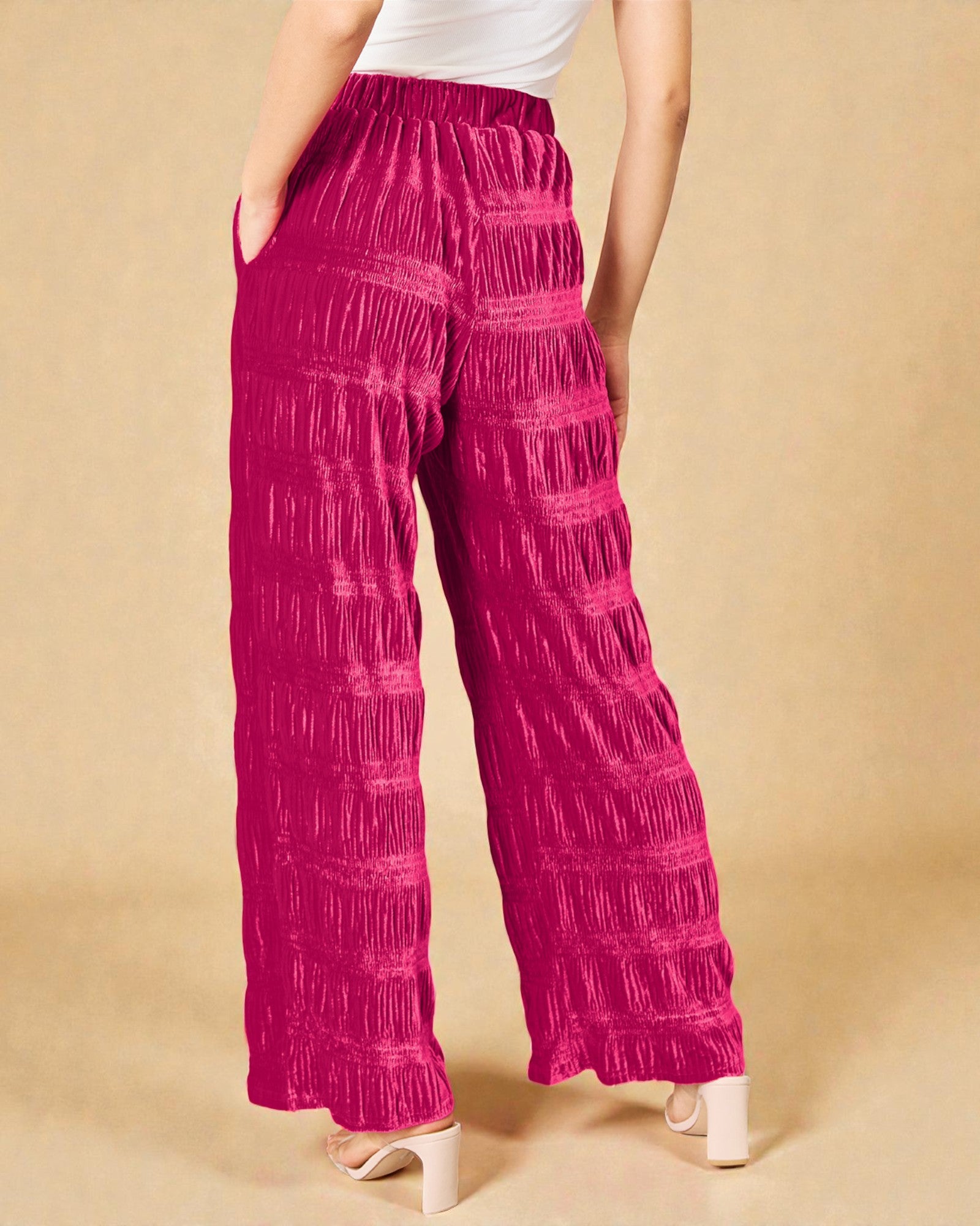 Person wearing bright pink patterned pants on a beige background