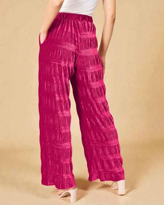 Person wearing bright pink patterned pants on a beige background