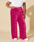 Person wearing bright pink pants and a white top on a beige background