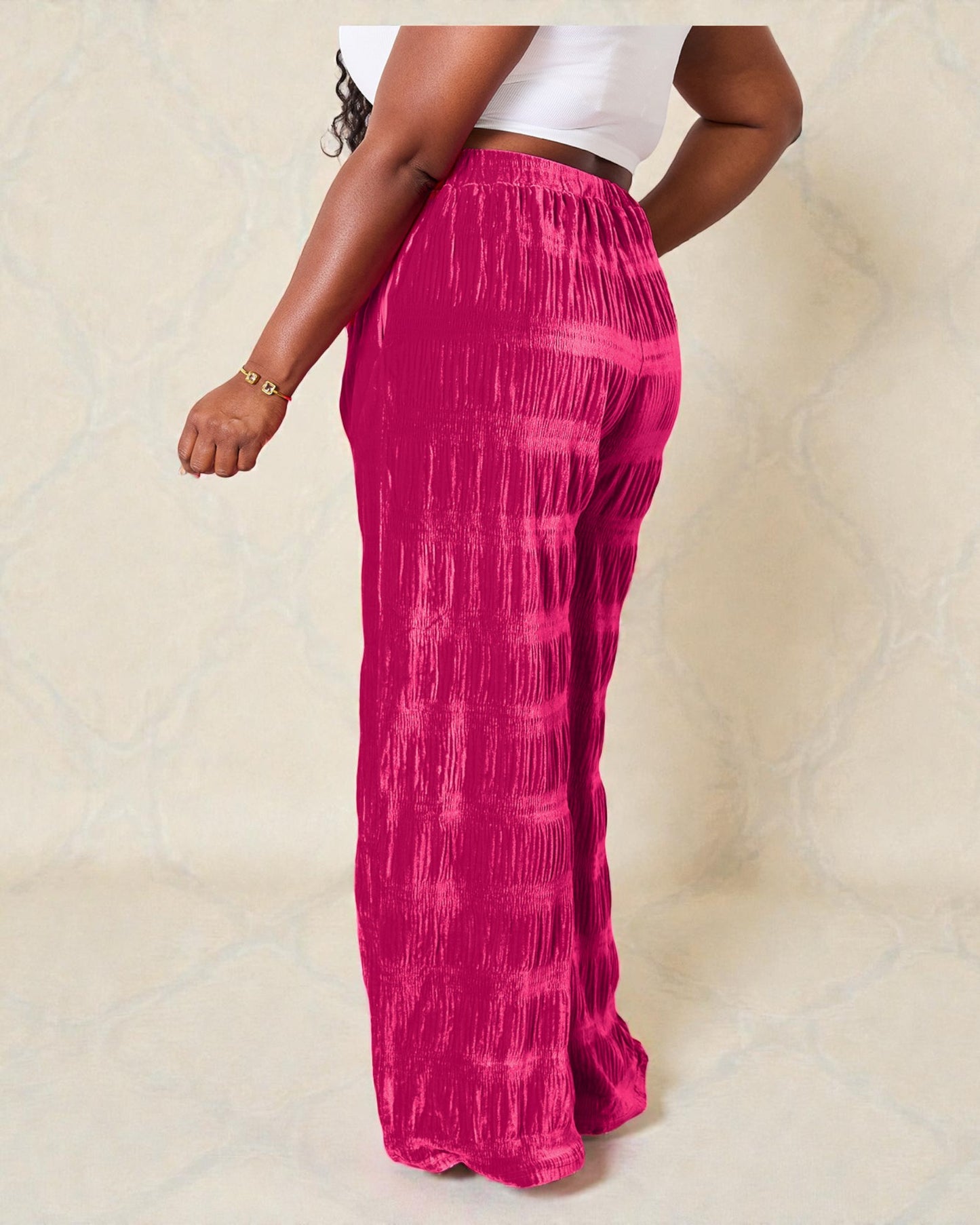 Person wearing bright pink tie-dye pants on a beige background