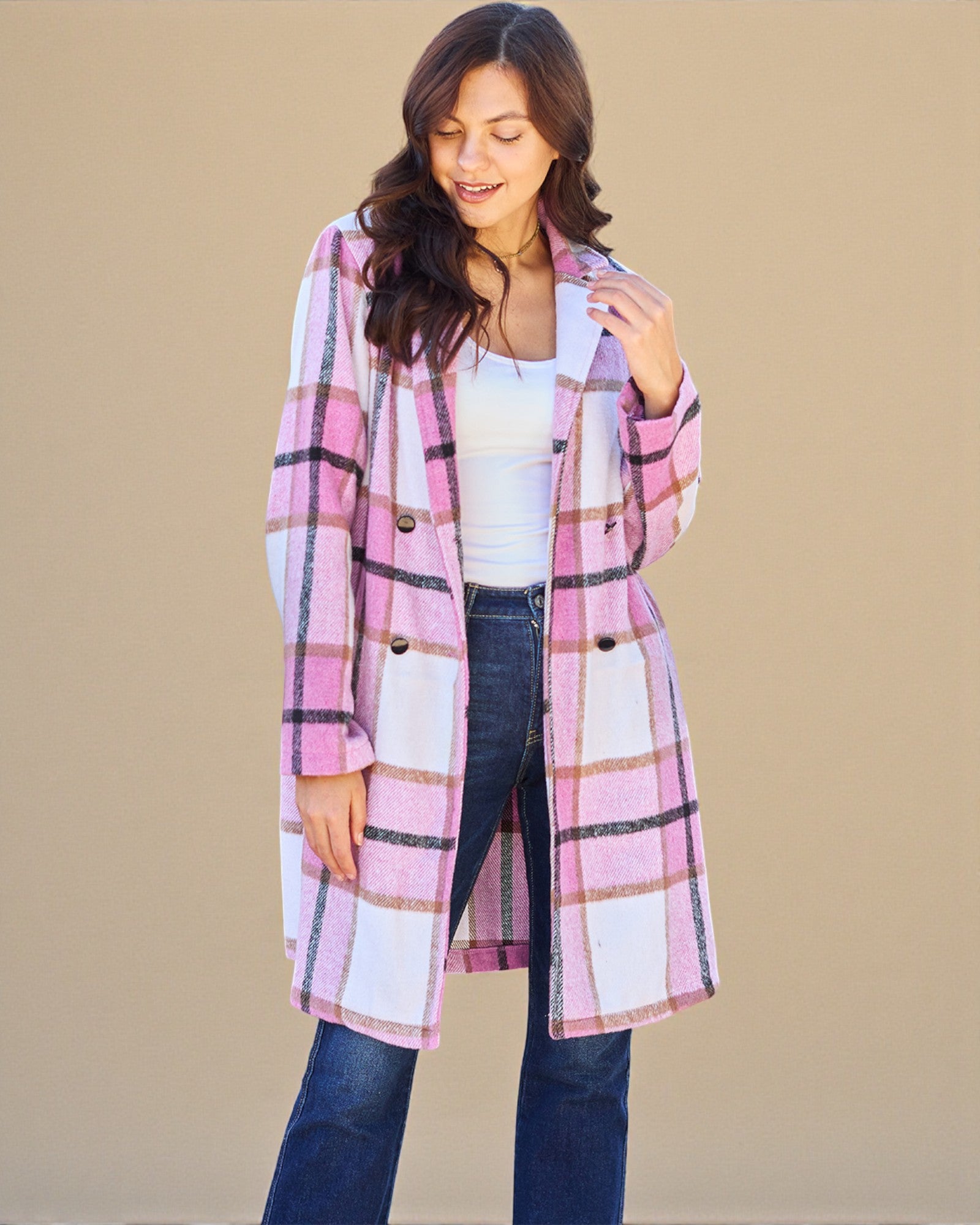 Woman wearing a pink and white plaid coat against a beige background