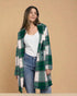 Woman wearing a green and white plaid coat against a beige background