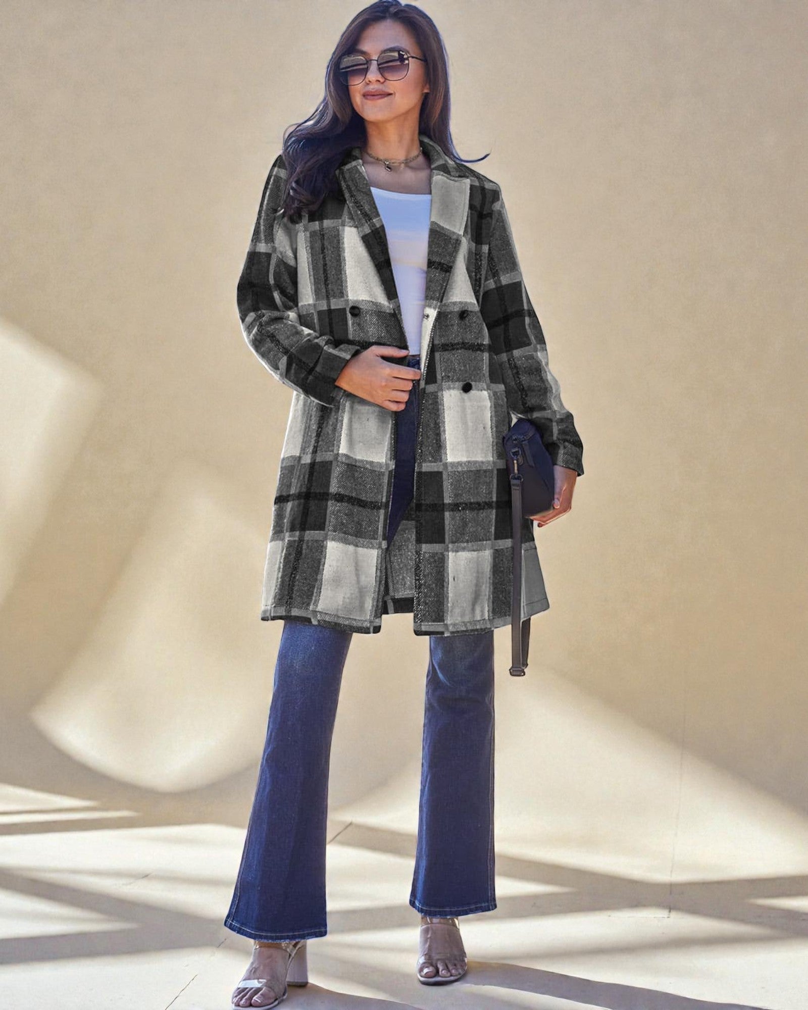 Woman wearing a plaid coat and blue jeans against a neutral background