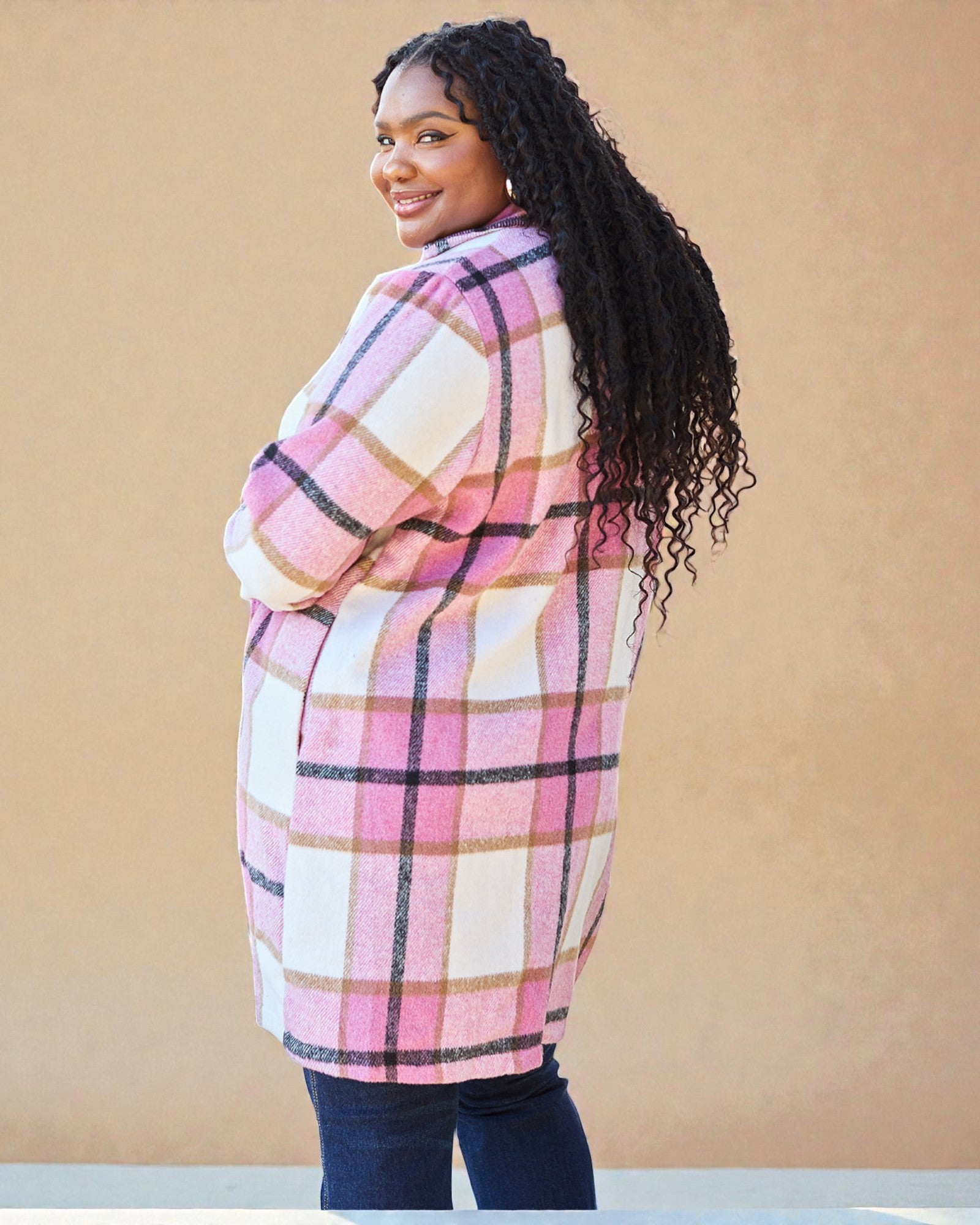 Woman wearing a pink and white plaid coat against a beige background