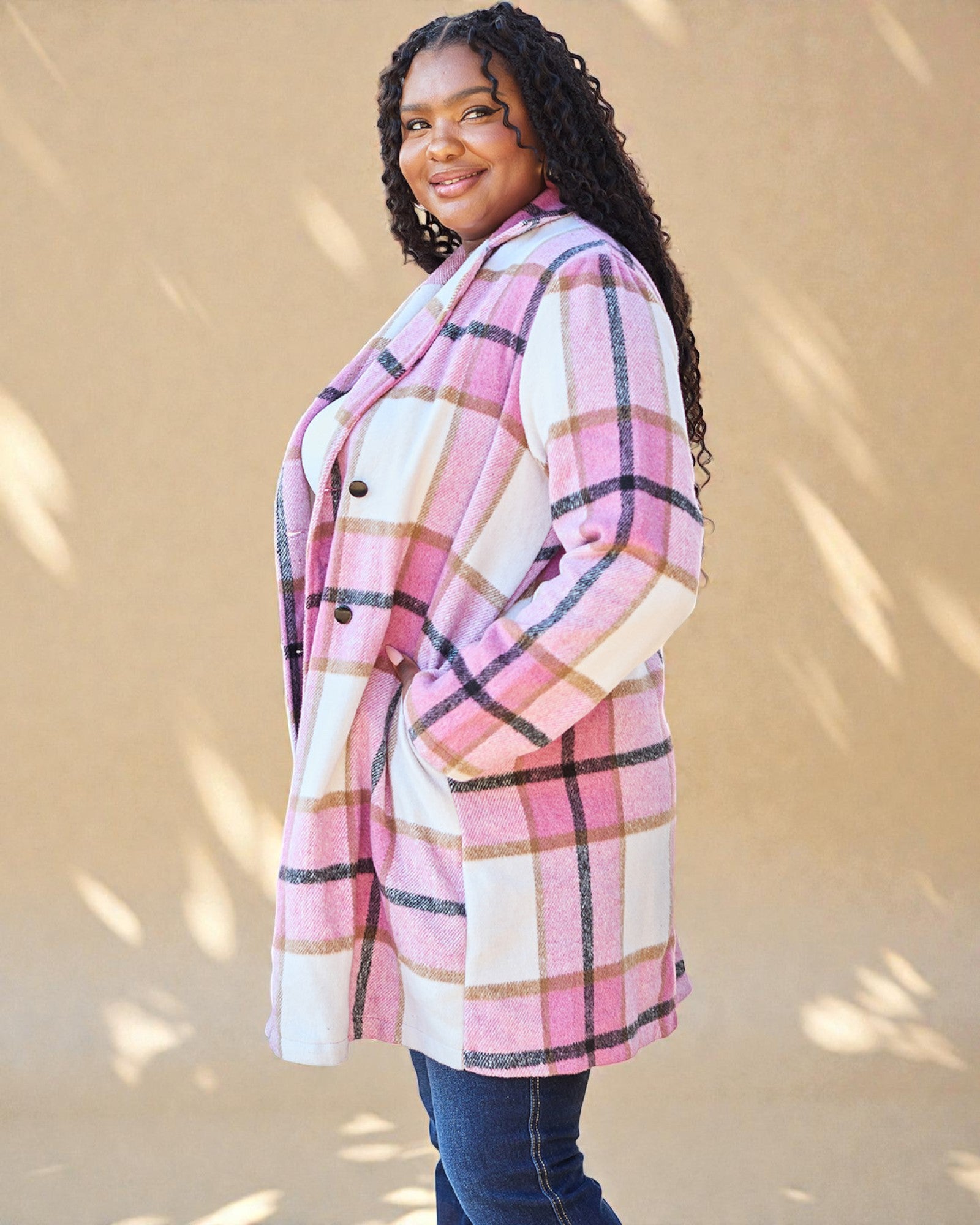 Woman wearing a pink and white plaid coat against a beige background