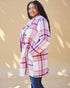 Woman wearing a pink and white plaid coat against a beige background