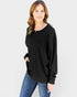 Woman wearing a black oversized sweater and blue jeans on a light gray background