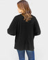 Person wearing a black oversized sweater and blue jeans on a white background