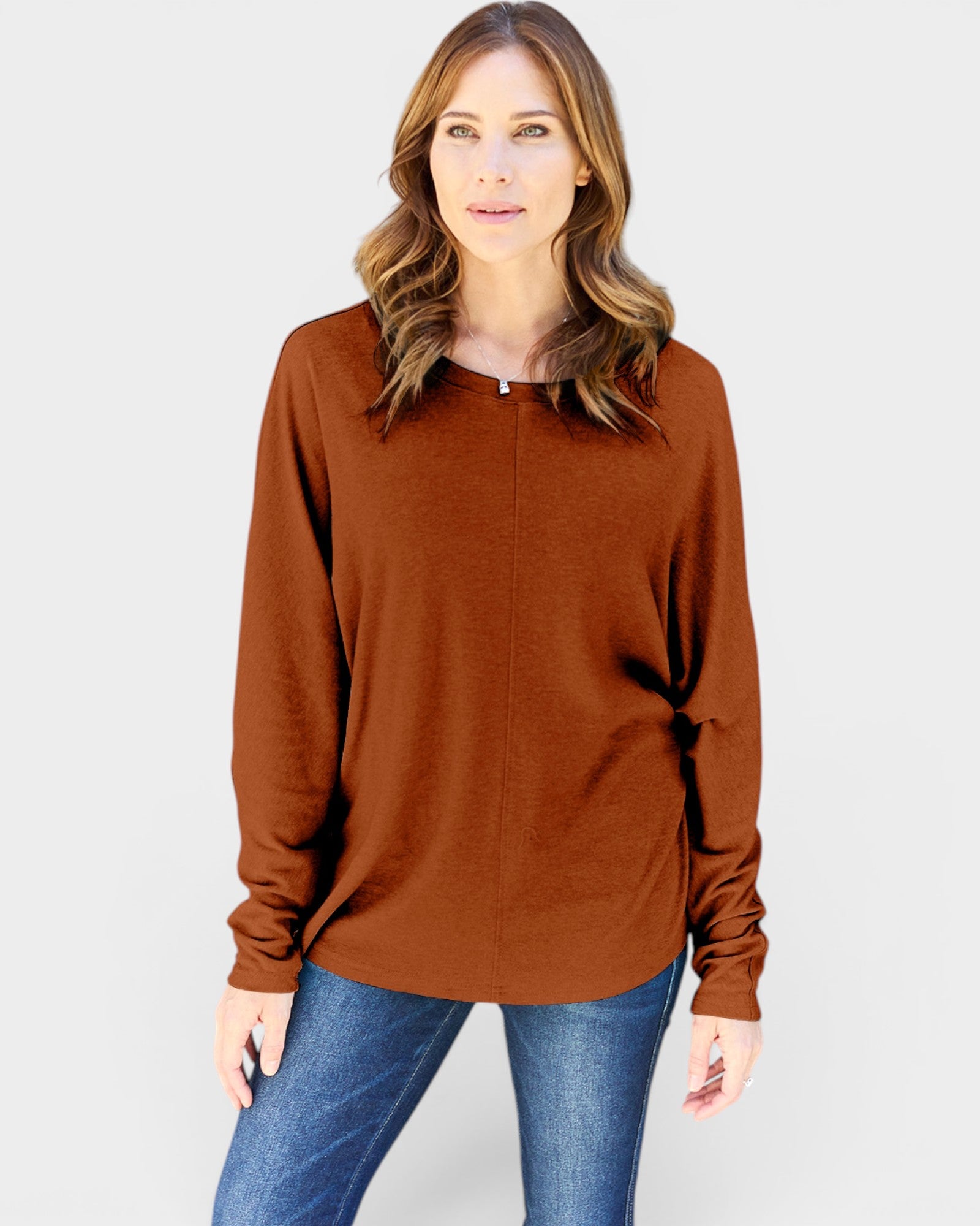 Woman wearing a brown sweater and blue jeans on a white background