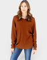 Woman wearing a brown sweater and blue jeans on a white background