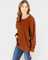 Woman wearing a brown sweater and blue jeans on a white background