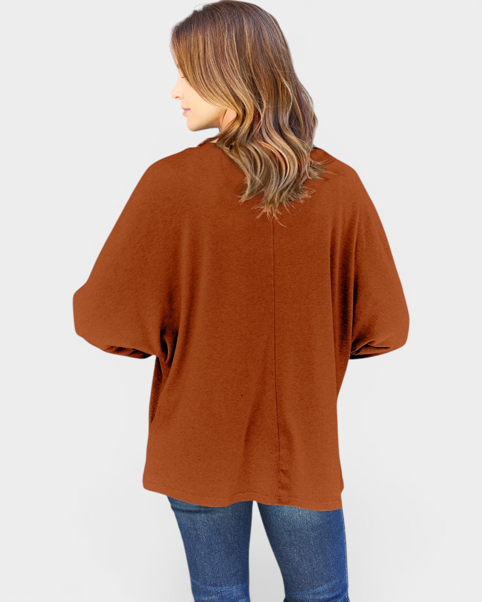 Person wearing a brown cardigan and blue jeans on a white background