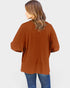 Person wearing a brown cardigan and blue jeans on a white background