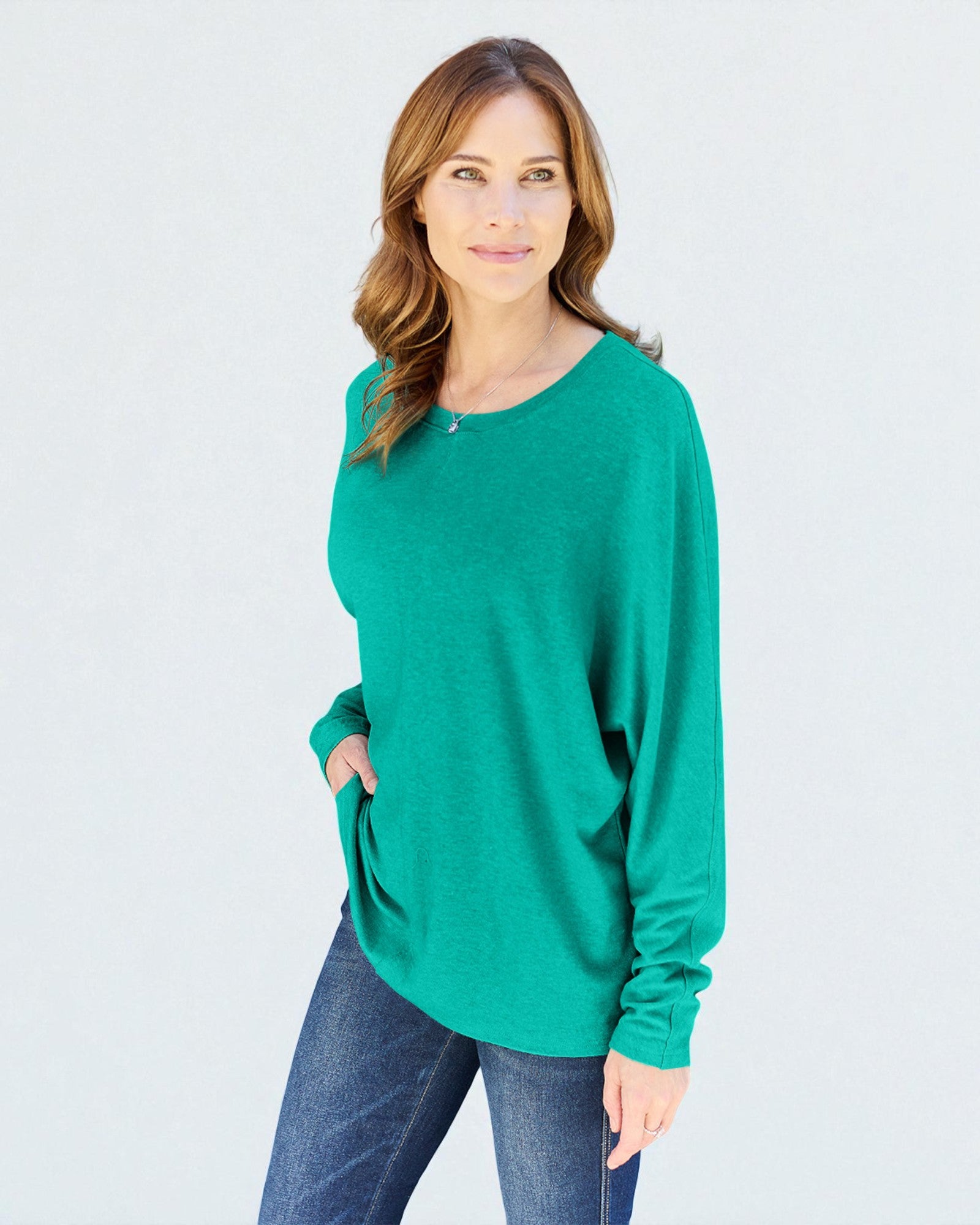 Woman wearing a green sweater and blue jeans on a white background