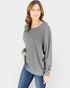 Woman wearing a gray long-sleeve top and blue jeans on a white background
