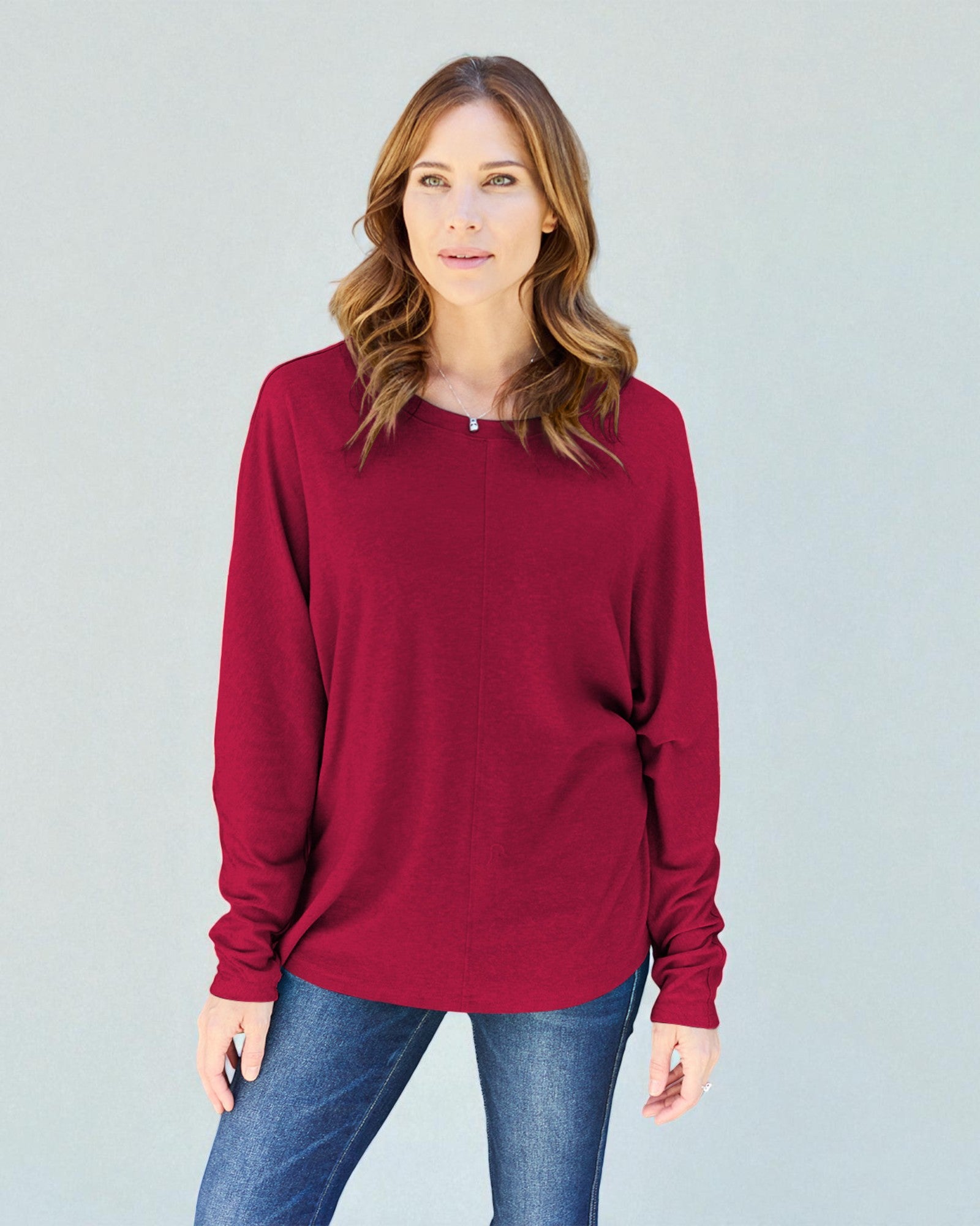 Woman wearing a red long-sleeve shirt against a gray background