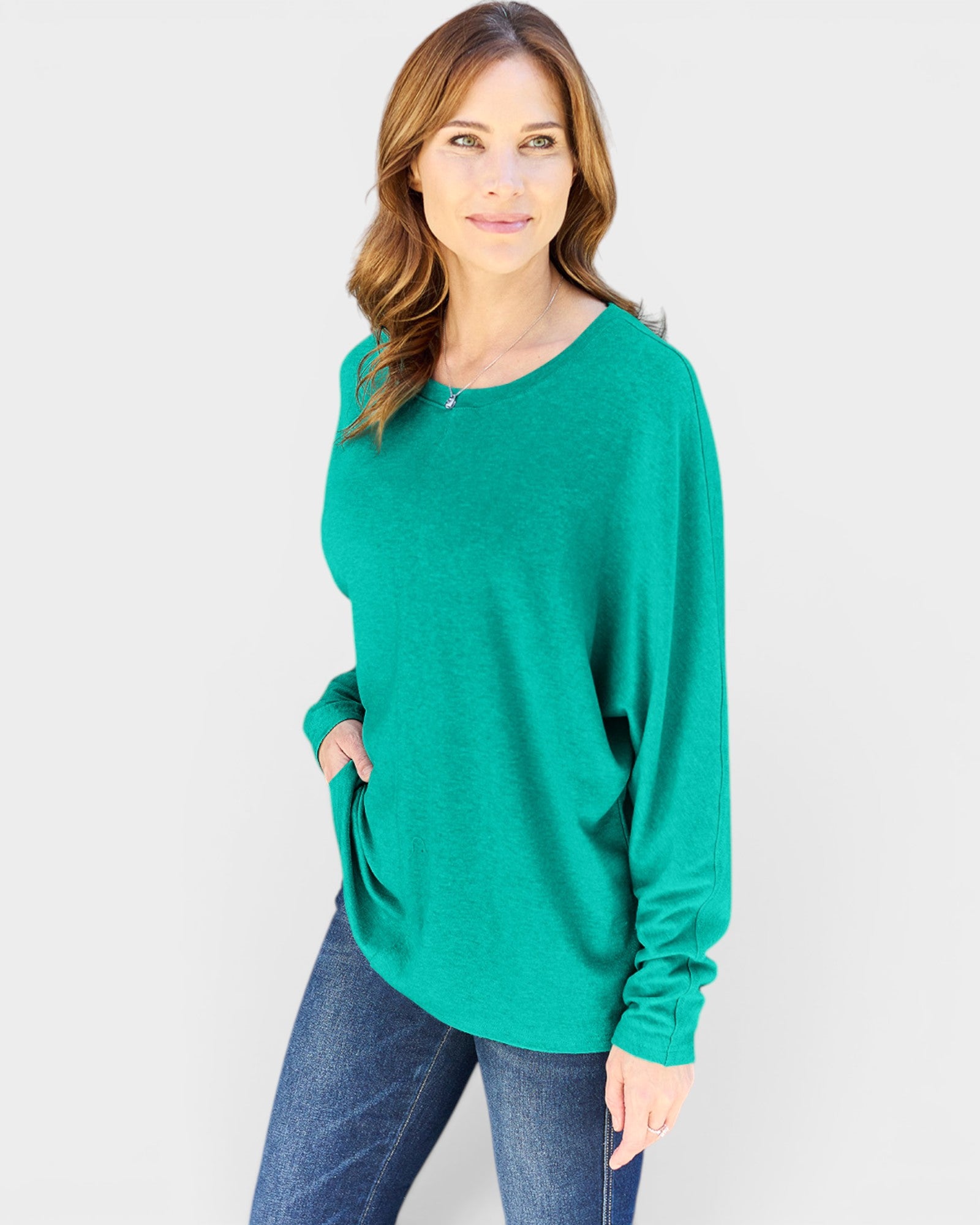 Woman wearing a green sweater and blue jeans on a white background