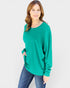 Woman wearing a green sweater and blue jeans on a white background