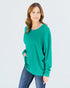 Woman wearing a green sweater and blue jeans on a white background