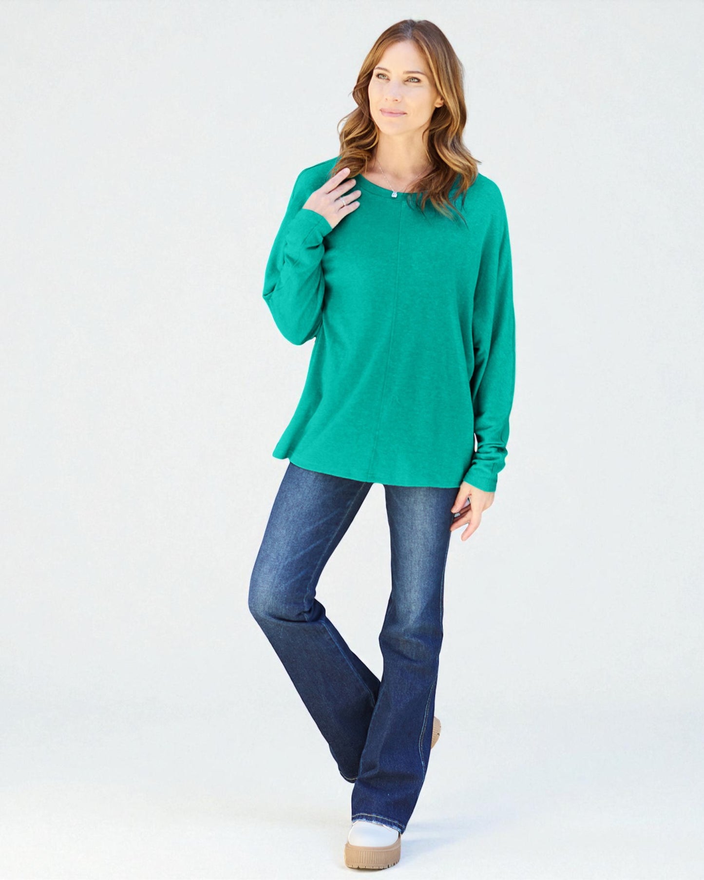Woman wearing a green sweater and blue jeans on a white background