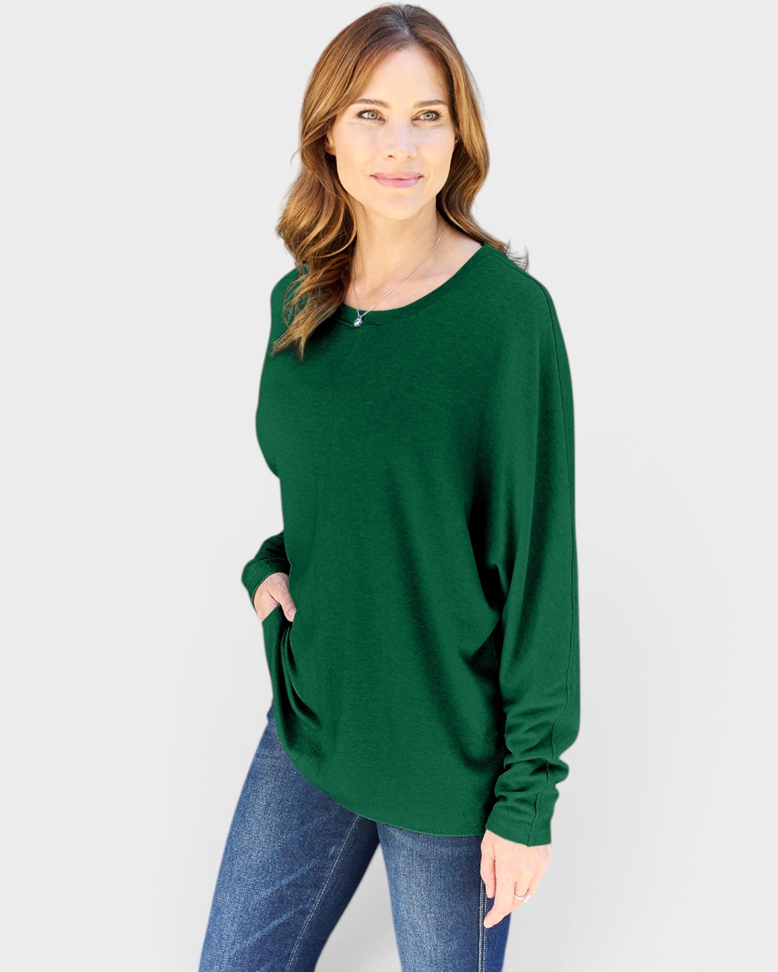 Woman wearing a green sweater and blue jeans on a white background