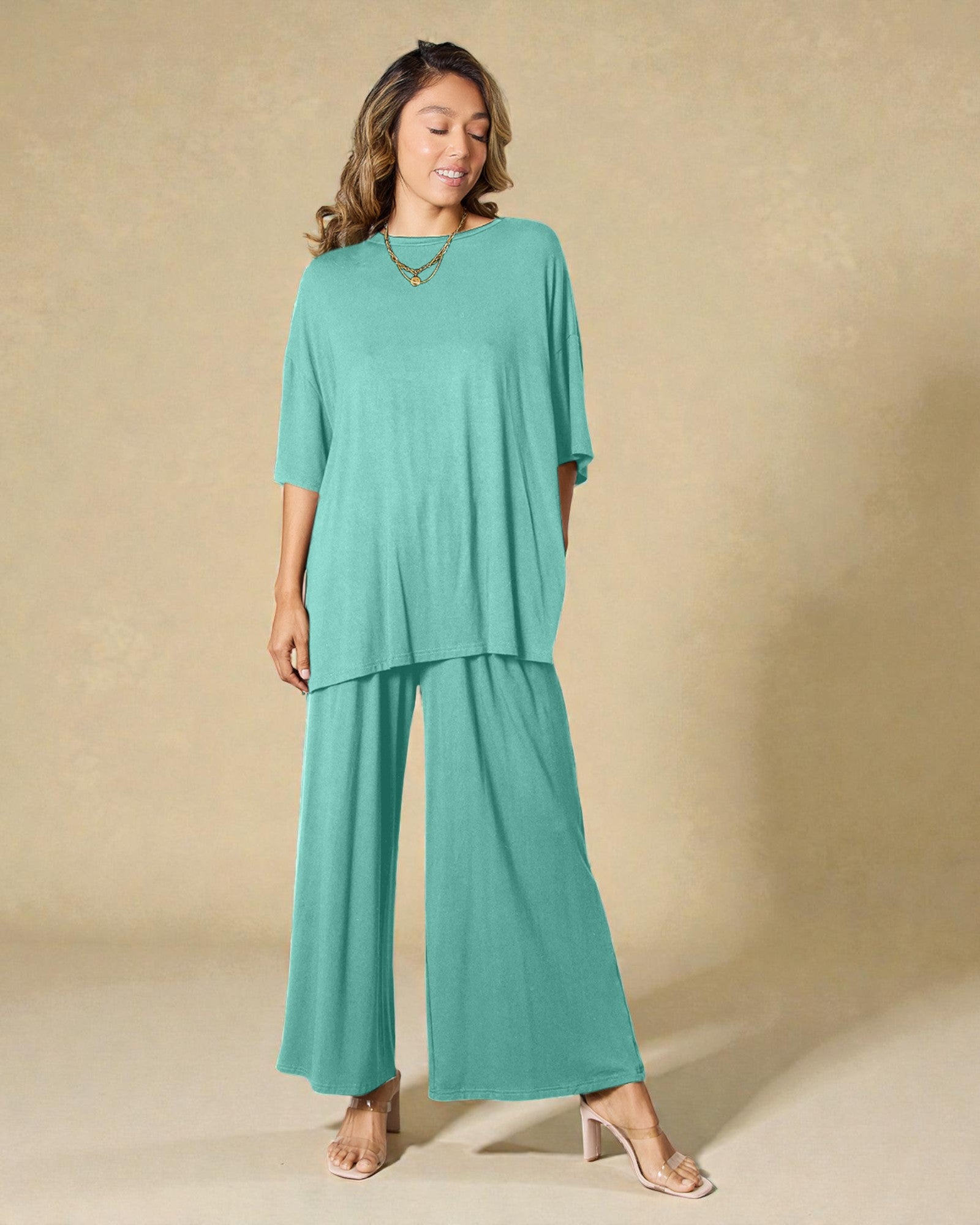 Woman wearing a teal outfit against a beige background