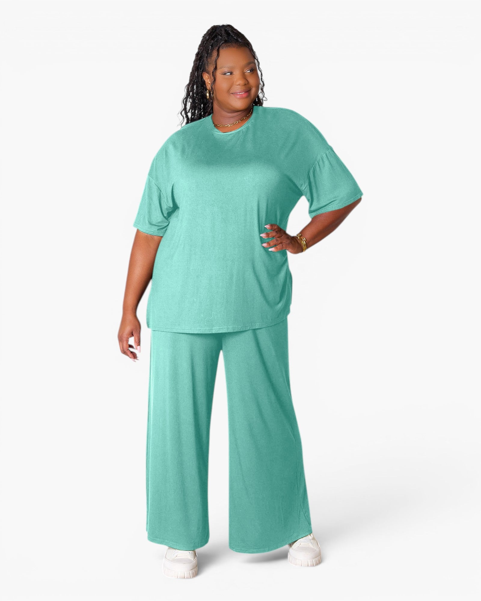 A woman modeling a matching two-piece lounge set in a bright mint green color, featuring a short-sleeve crewneck top and wide-leg pants, against a plain white studio background.