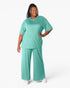 A woman modeling a matching two-piece lounge set in a bright mint green color, featuring a short-sleeve crewneck top and wide-leg pants, against a plain white studio background.