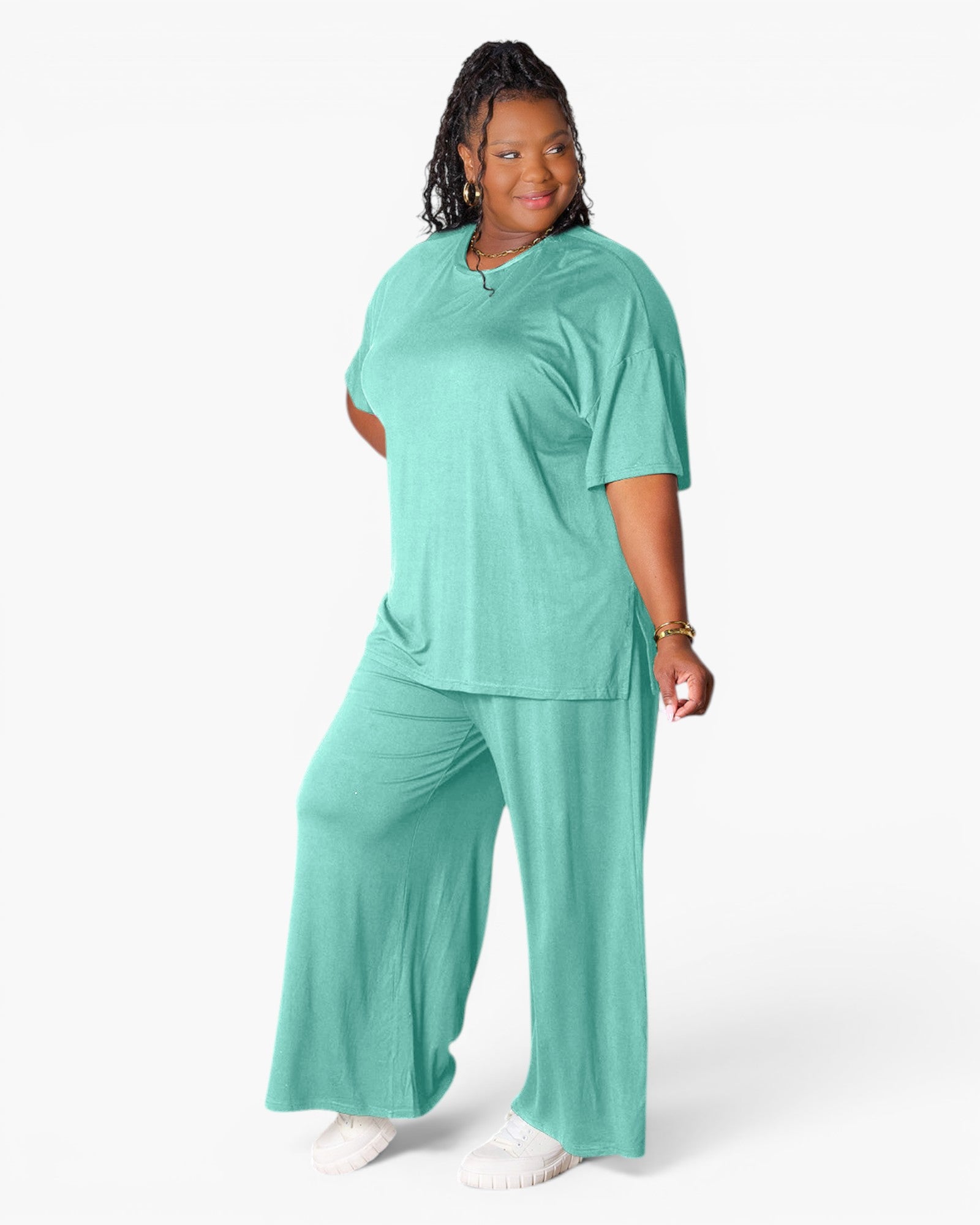 A woman modeling a matching two-piece lounge set in a soft mint green color, featuring a short-sleeve V-neck top and wide-leg pants, against a plain white studio background.