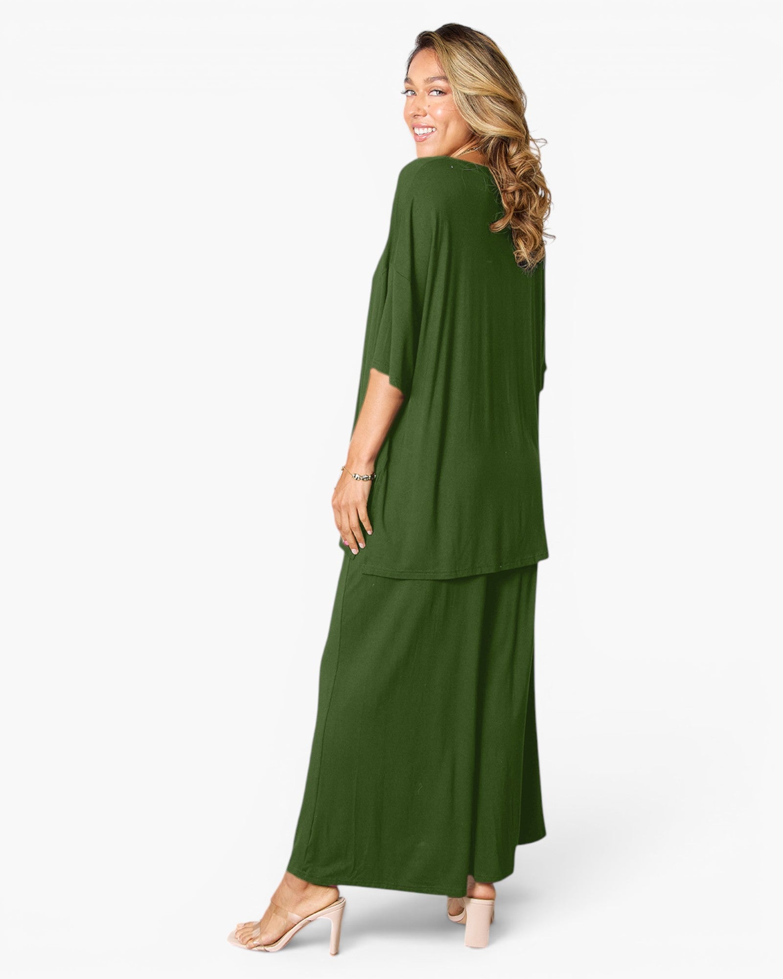 A woman modeling a matching olive green two-piece outfit consisting of a draped long-sleeve top and wide-leg pants, shown from a three-quarters back view against a light gray studio background.